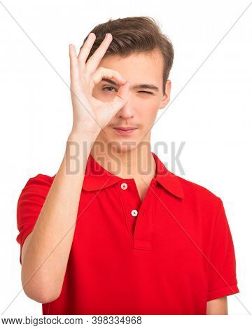 Portrait of happy young man showing okay gesture, isolated over white background. Photo of  Handsome white guy in a red shirt with sign OK.  Male person shows gesture OKAY .