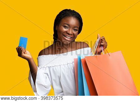 Easy Payments. Smiling Black Young Woman Holding Shopping Bags And Credit Card With Contactless Payp