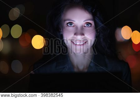 Portrait Of Brunette Woman At Laptop At Night Against Background Of Garlands. Recycling Work In Even