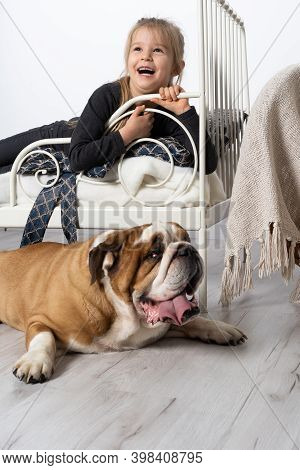 In The Girls Bedroom There Is An English Bulldog Next To Her Bed And The Child Is Lying On The Bed A