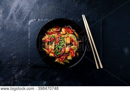 Udon Stir Fry Noodles With Chicken And Vegetables On Black Background. Hot Wok With Chicken Steaming