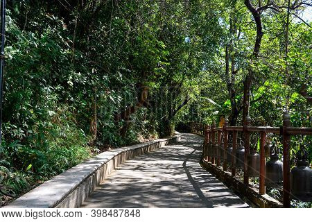 Walkway In The Forest With Buddhist Temple Bells - Chiang Rai, Thailand.  Walkway Bells In The Templ