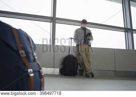 Young Asian Man Male Air Traveler Reading E-book Using A E-reader While Waiting For Boarding In Airp