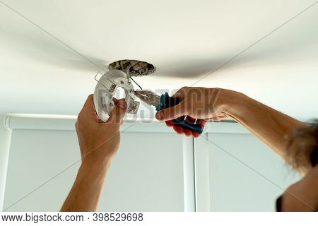 Man Hands Installing Socket For Light Bulb. Repairs Ceiling Light Indoor Home In White Room
