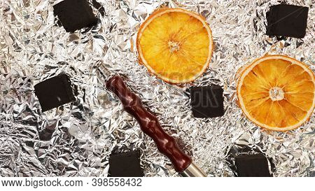 Coals For Hookah On Foil Background With Dry Oranges And Hookah Pipe - Top View