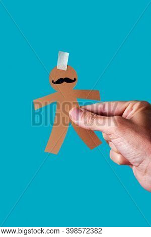man with a paper man doll in his hand, as a prank for dia de los inocentes, the innocents day, a feast held in spain, hispanic america and philippines equivalent to april fools day, blue background