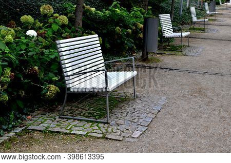 Benches With Metallic Shiny Stainless Steel Construction, Armrests, White Wood Paneling In Public Pa