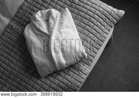 White Fluffy Cotton Bathrobe Lay In Hotel On Bed. Bath Robe Fold On Blanket. Cozy Home Clothing.