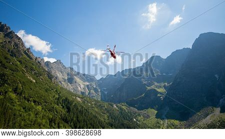 Red Helicopter Is Flying Between Mountains Peak, Summer Time