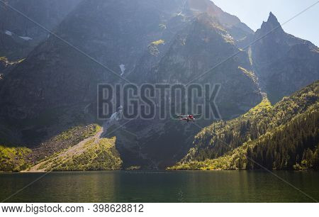 Red Helicopter Is Flying Between Mountains Peak, Summer Time