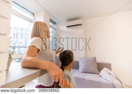 Mother In Sportswear With Daughter Standing Near The Air Conditioning