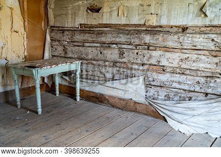 Old, Rotting Walls In An Abandoned Building With A Table Pushed In The Corner