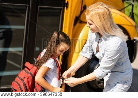 Mother Brings Her Daughter To School Near The School Bus. Back To School
