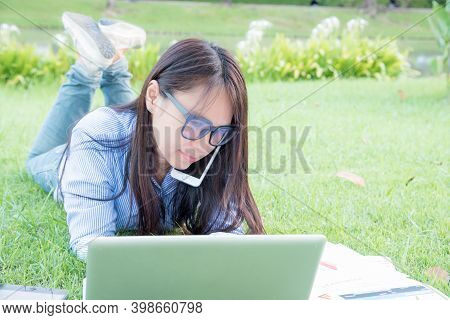 Serious Businesswoman Laydown And Work Hard On A Green Grass Fields.