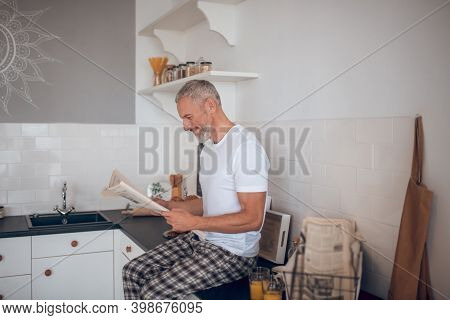 Grey-haired Tall Man Reading A Newspapaer And Looking Interested