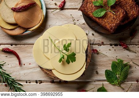high angle view of some slices of vegan cheese, some tofu fillets and some cold cuts made of tofu, on a white rustic table