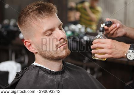 Close Up Of A Male Clietn Being Sprayed With Cologne At The Barbershop After Getting A New Haircut A