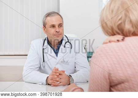 Mature Male Doctor Looking Seriously At His Senior Patient. General Practitioner Having Medical Appo