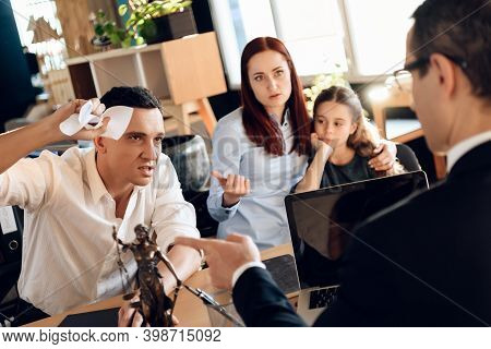 Frustrated Father In Suit Sits On Couch Next To Young Wife And Daughter. A Man Sits In A Suit And Lo