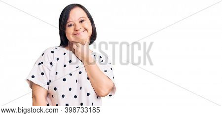 Brunette woman with down syndrome wearing casual clothes looking confident at the camera smiling with crossed arms and hand raised on chin. thinking positive. 