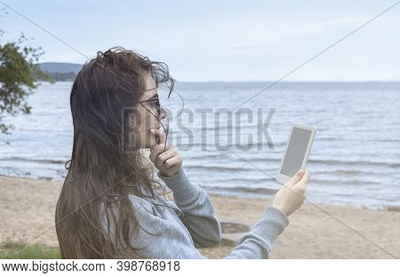 Reading A E-book On The Beach. Holding A E-book