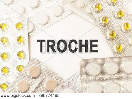 Text Troche On White Background. There Are Various Pills And Vitamins Around. Medicine Concept