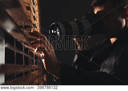 Private Detective With Camera Spying Near Window Indoors