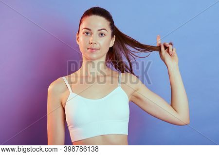 Young Pretty Fitness Woman Pulling Her Ponytail Aside Posing Isolated Over Color Background, Looking