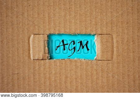 A Cut-out Hole In The Paper Cardboard, And Under It A Piece Of Paper With The Word Agm. The Word Agm
