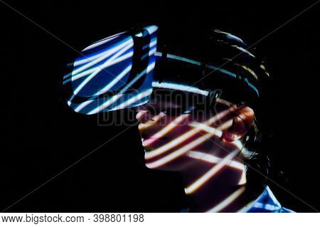 Woman Using Virtual Reality Headset And Looking Around At Interactive Technology Exhibition With Col
