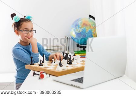 Portrait Caucasian Little Cirly Girl Playing Chess At The Table In Interior With Chessboard. Little 
