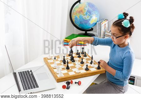 Portrait Caucasian Little Cirly Girl Playing Chess At The Table In Interior With Chessboard. Little 