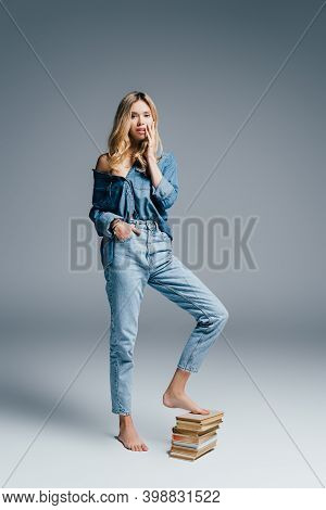 Seductive Young Woman In Denim Shirt With Books Isolated On Grey Background
