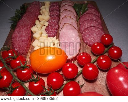Slicing Smoked Sausage Of Four Varieties With Cheese And Red And Yellow Tomatoes And Cherry Tomatoes