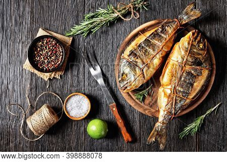 Hot Smoked Gilt-head Sea Bream, Orata, Dorado Fish On A Wooden Round Cutting Board On A Dark Wooden 