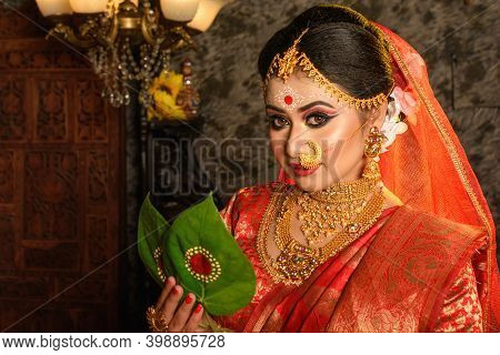 Portrait Of Very Beautiful Indian Bride Holding Betel Leaf, Bengali Bride In Traditional Wedding Sar
