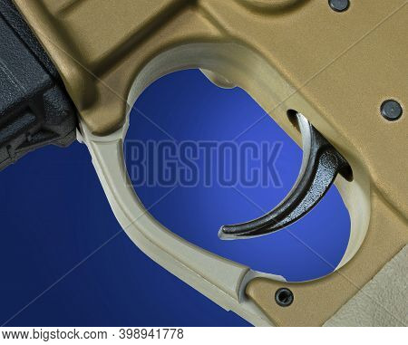 Trigger From A Copper Colored Ar-15 On A Blue Background