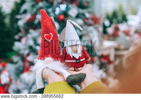 The Girl Holds Tomte And The Gnome In Her Arms. Against The Background Of A Christmas Tree In The St