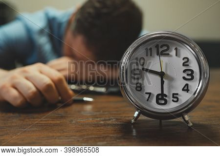 The Clock Shows Half Past Nine In The Evening. Man Fell Asleep At Work.