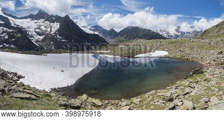 Panoramic View Of Glacial Lake With Springs From Melting Ice Glacier With Sharp Snow-capped Mountain