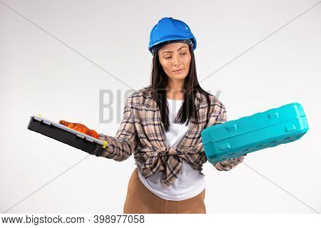 Handywoman In A Helmet, Blue Hard Hat Looking At Two Suitcases For Tools. Combat Gender Stereotypes.