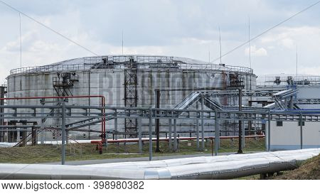 Refinery Factory Oil Storage Tank And Pipeline Steel At Day On Framatic Sky Background. Oil Refinery