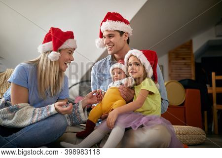 Cheerful parents spening Christmas time together with their kids at home