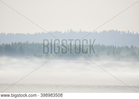 Wild River Bank With Meadow And Trees In Morning Fog