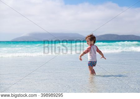 Smiling Little Boy Enters To The Water Sea Alone In Cabo Frio Beach, Brazil.caucasian Child With The