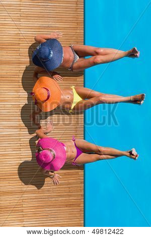 Three women reaxing on the deck by the swimming pool at exotic resort
