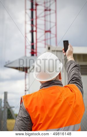 Employee with the cell phone near to gsm tower before the rain