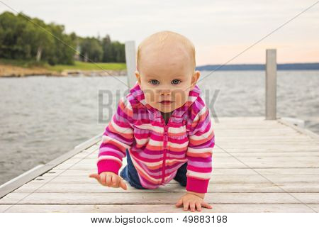 Little girl crawling on the dock