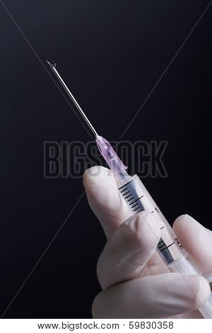 Hand in latex gloves holding syringe