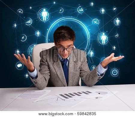 Young businessman sitting at desc with social network icons
